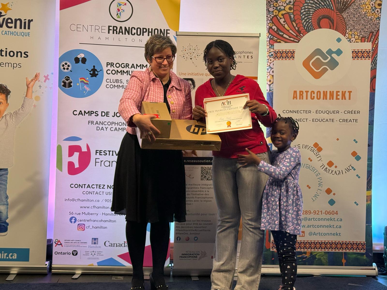 Remise du 1er Prix Categorie de 14-17ans Un Ordinateur Portable par Nabila  la Représentante de la Communauté Francophone Accueillante(CFA) de Hamilton